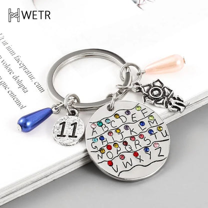 Llavero con el alfabeto inglés de la serie de televisión Strange Things para hombres y mujeres, plateado, colorido, para mochila, accesorio para llave de coche.